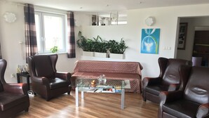 Una sala de estar con sillones de cuero, una mesa de centro de vidrio, un sofá y plantas en macetas.