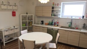 Una cocina moderna con una mesa de comedor blanca, dos sillas, armarios de madera y una ventana.