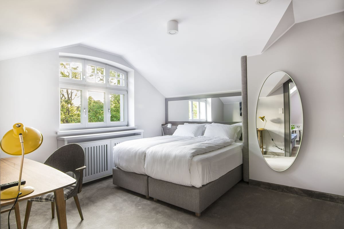 Une chambre avec une grande fenêtre, un lit, un bureau et une chaise.