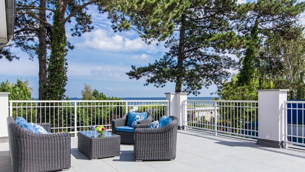 An outdoor seating area with wicker furniture and a view of the sea. - Villa Testa (Sopot)