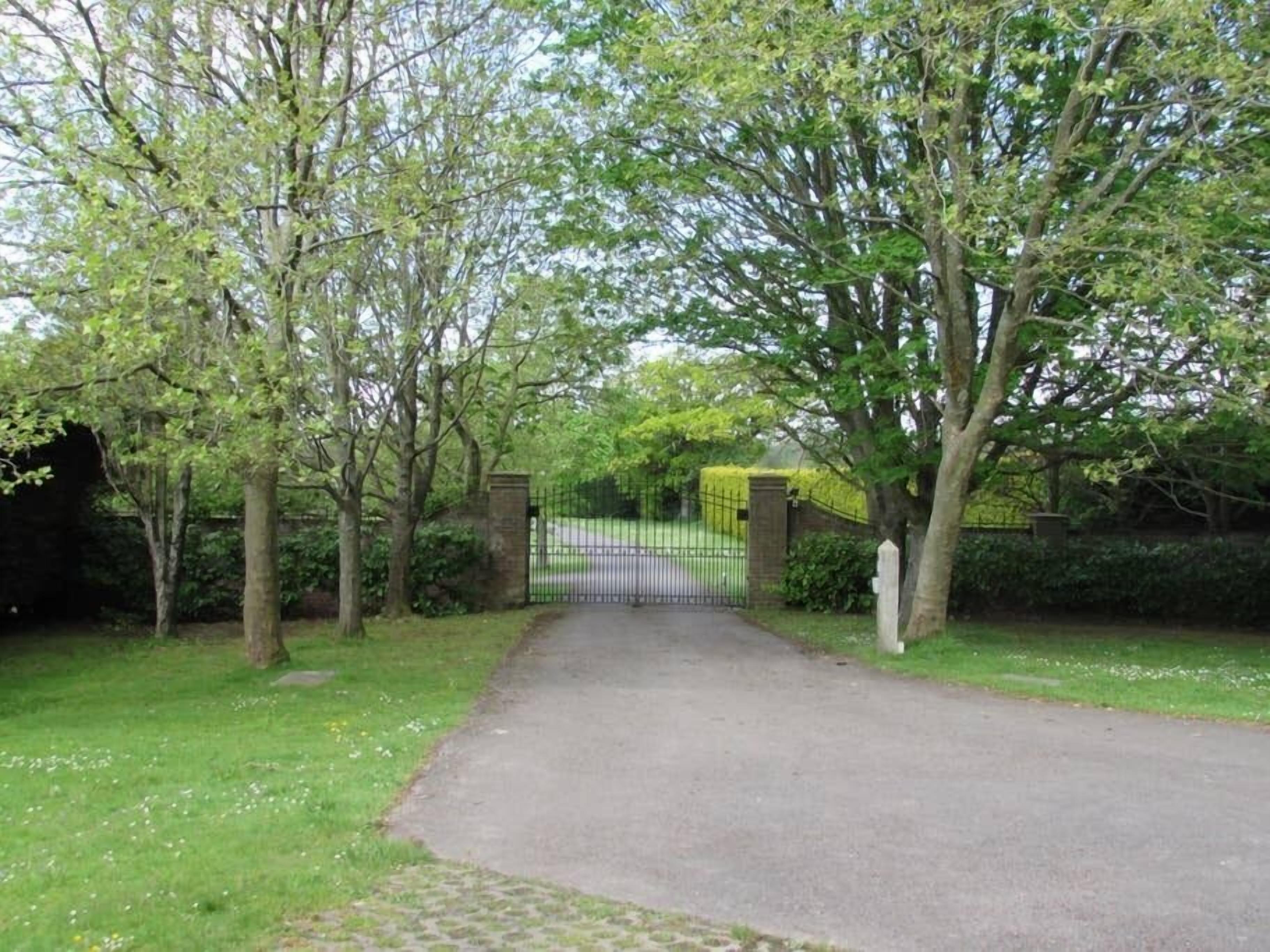 A gated driveway leading to a property surrounded by trees and greenery.
