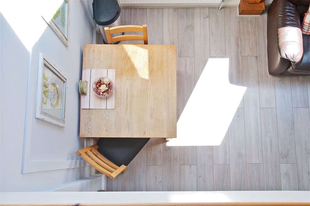 A dining area with a wooden table, chairs, and a bowl of food.