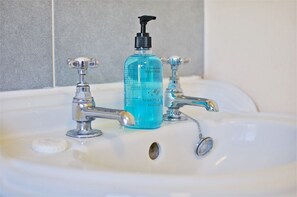 Un lavabo de salle de bain avec deux robinets et un flacon de savon liquide pour les mains.