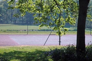Un terrain de sport entouré de clôtures, doté d’un filet, et bordé de pelouse et d’arbres.