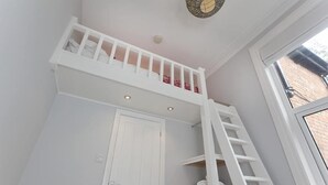 Una habitación con una puerta y una escalera blancos, y un ventanal.