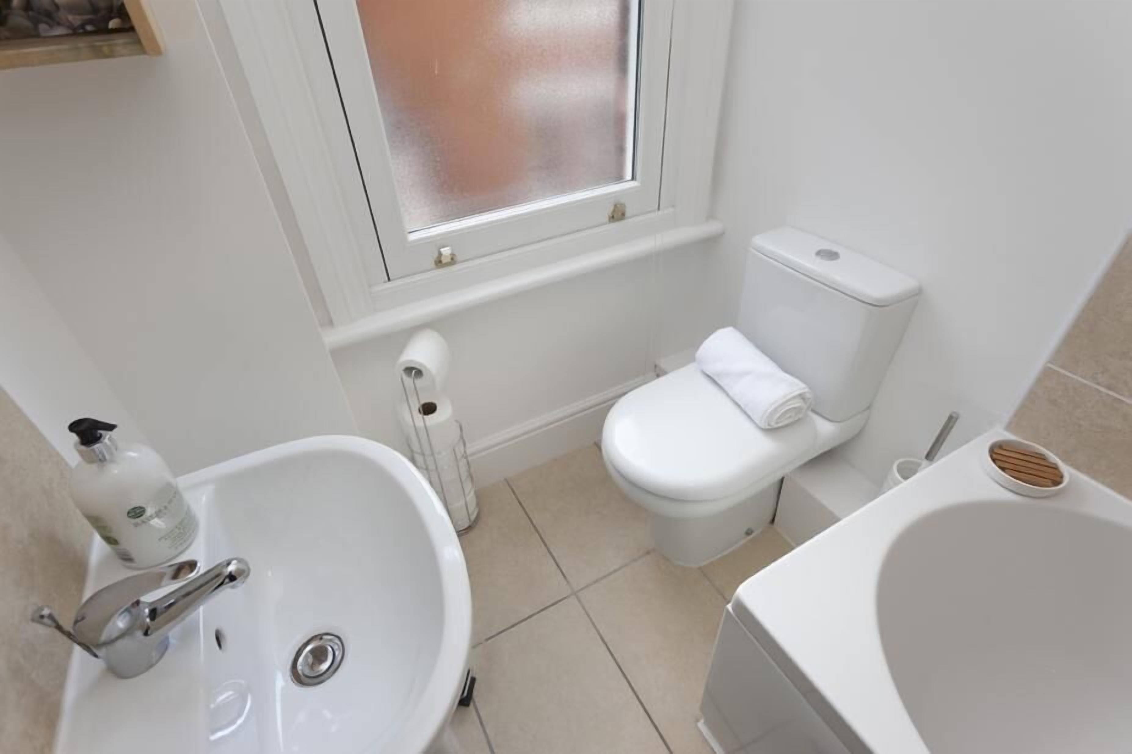 A small, clean bathroom with a white sink, toilet, and bathtub.