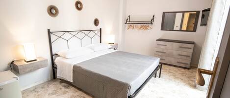A bedroom with a bed, bedside tables, a dresser, and a mirror.