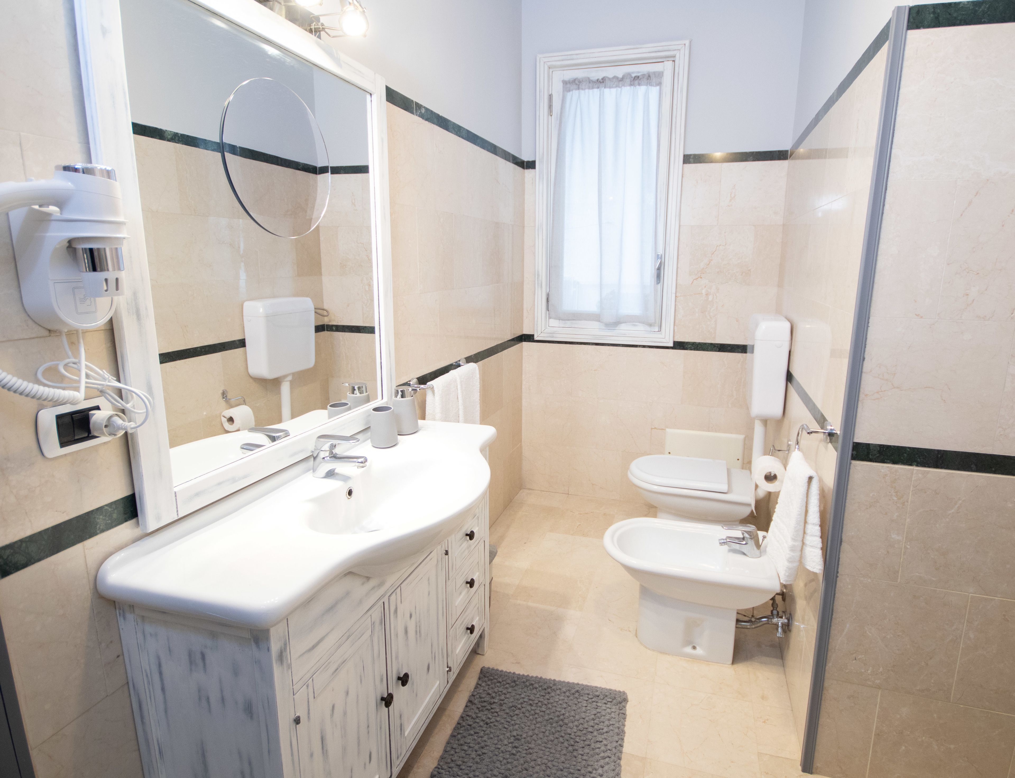 A bathroom with a white sink, mirror, and toilet. There is a towel rack and a shower area.