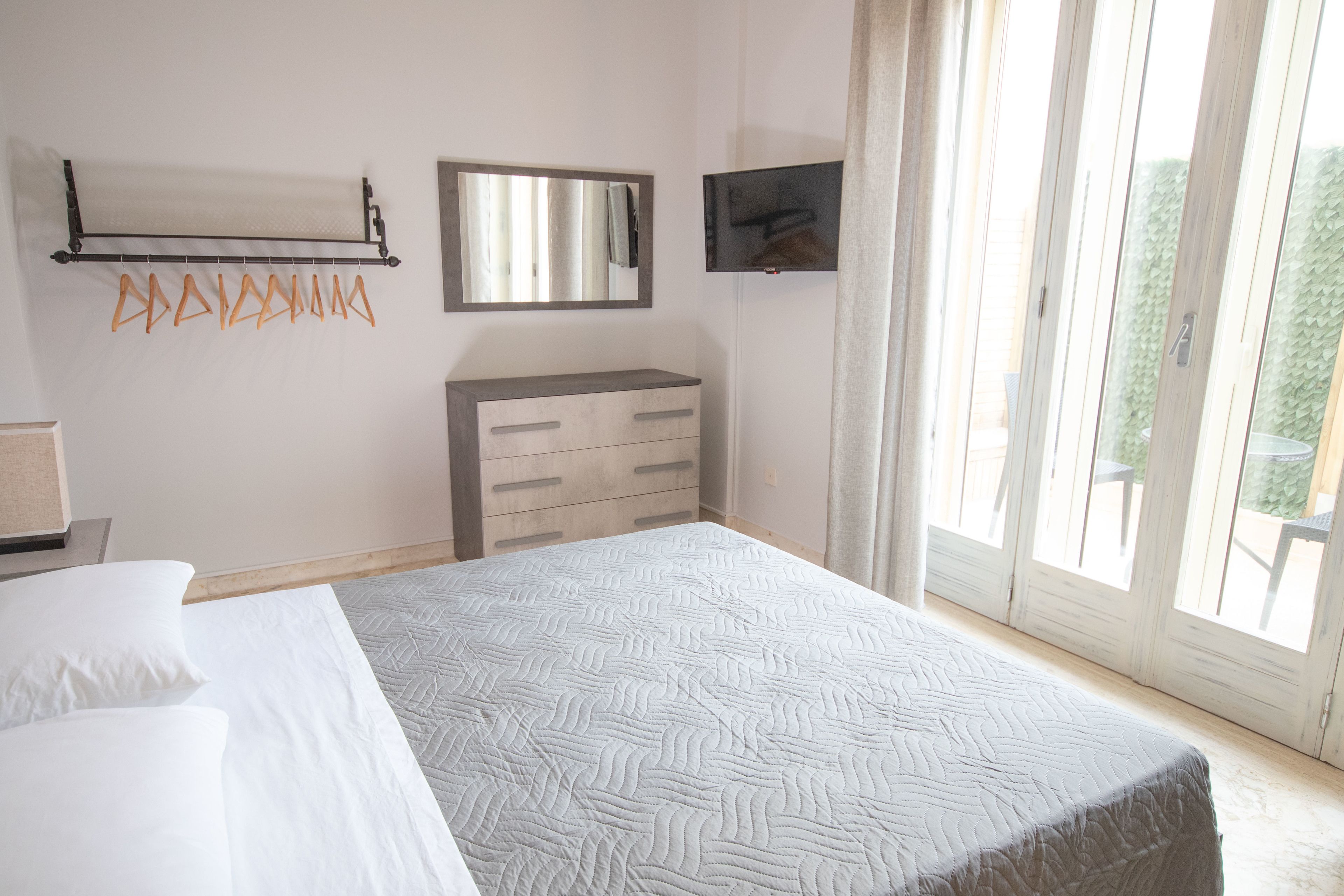 Ein Schlafzimmer mit Bett, Schminktisch, Spiegel und Fernseher.