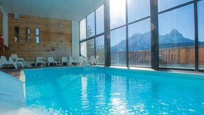 Una piscina interior con vistas despejadas a montañas a través de amplios ventanales.