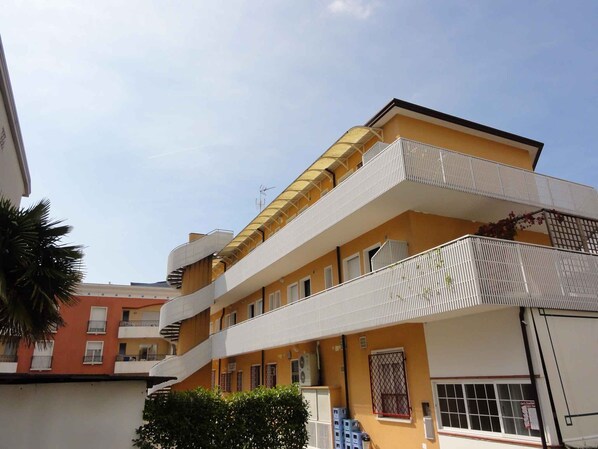 A multi-story building with balconies, a staircase, and a clear sky.