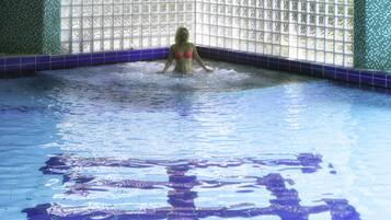 Una piscina techada, una piscina al aire libre, sombrillas