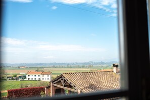 A view of a rural landscape with a large building with a tiled roof and a chimney, surrounded by fields and a clear sky. - La Locanda di Corrado (Cerreto Guidi)