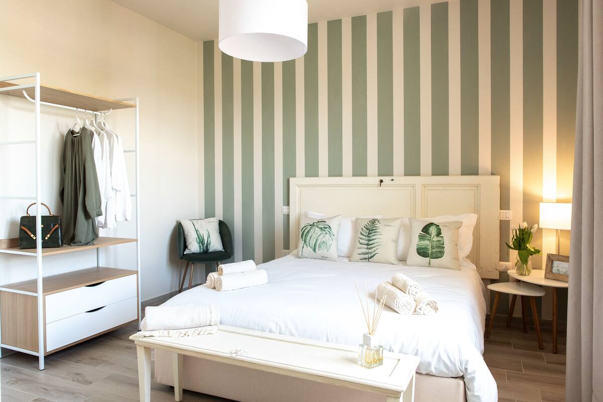 Een netjes ingerichte hotelkamer met een bed, nachtkastje en een kledingkast.