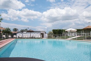 A swimming pool with lounge chairs and umbrellas, surrounded by buildings and trees. - La Locanda di Corrado (Cerreto Guidi)