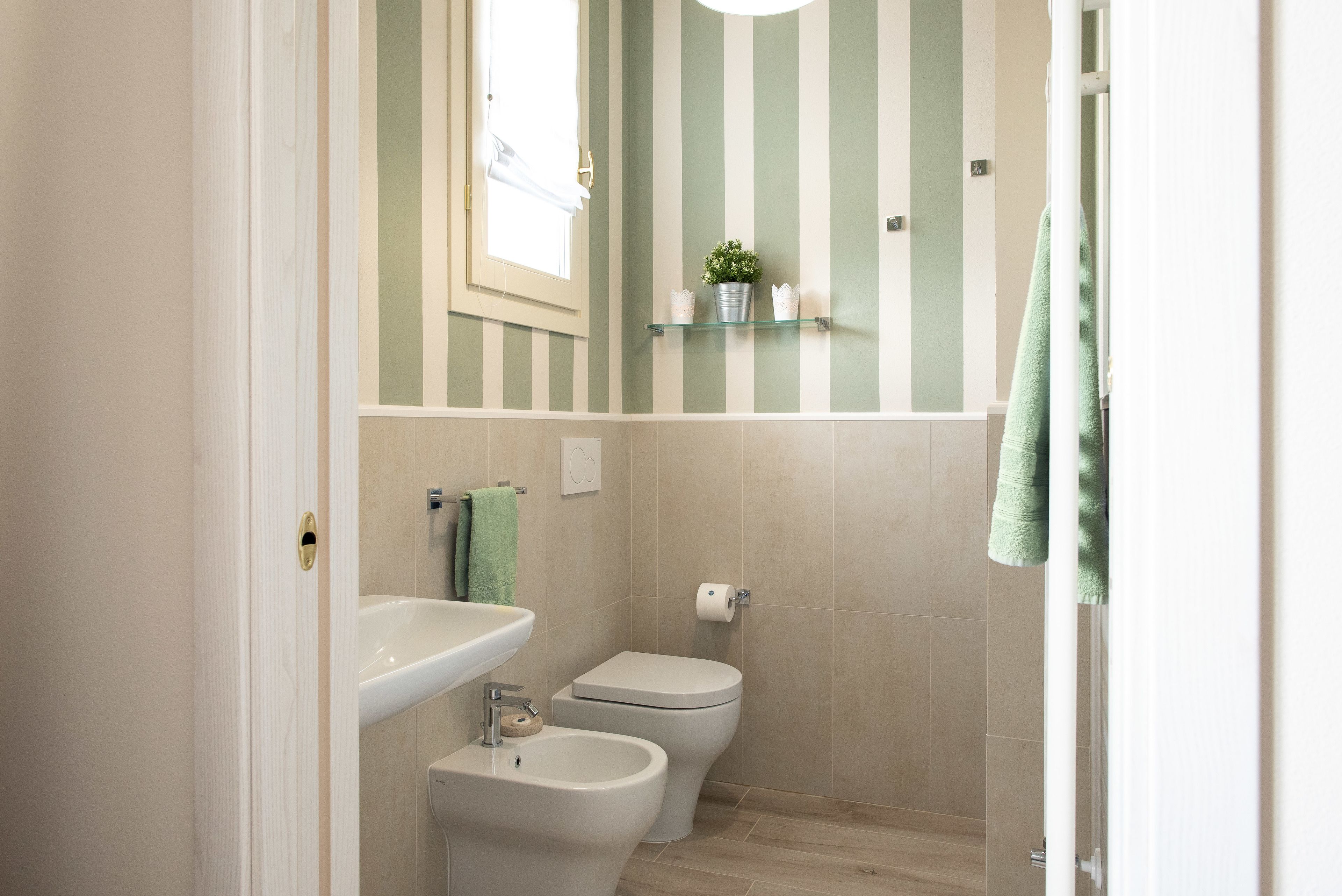 Un bagno con parete a righe, un lavandino, un bidet e un water.