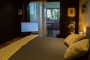 A hotel room with a bed, a television, a window, and a view of an outdoor seating area. - Country Hub Milano (Mediglia)