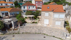 Un théâtre en pierre doté d’une scène centrale et d’une zone réservée au public, entouré d’immeubles d’habitation aux toits recouverts de tuiles rouges.