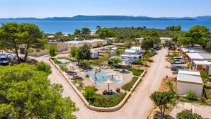 A campsite with RVs, a swimming pool, and a view of the sea. - Mobile Homes at Camping Ugljan Resort (Preko)