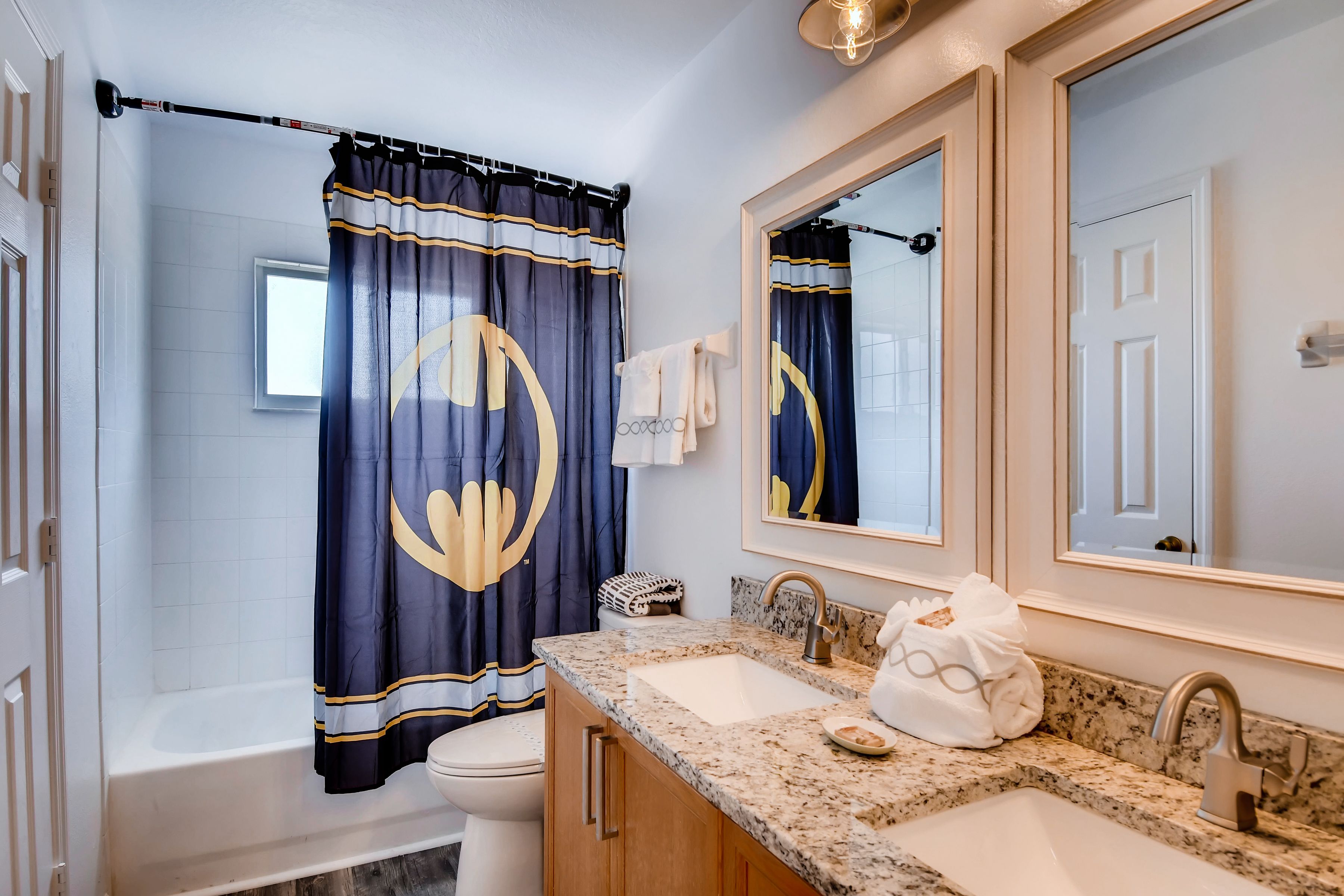 A bathroom with a bathtub, two sinks, a large mirror, and a shower curtain with a circular design.