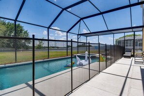 A covered outdoor swimming pool with a fence, inflatable swan float, and lounge chairs.