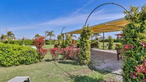 Un jardin bien entretenu, agrémenté d’une pergola, d’un espace détente et d’une variété de plantes.