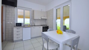 Une cuisine moderne avec des meubles blancs, un four à micro-ondes, un évier et une table à manger avec des chaises.