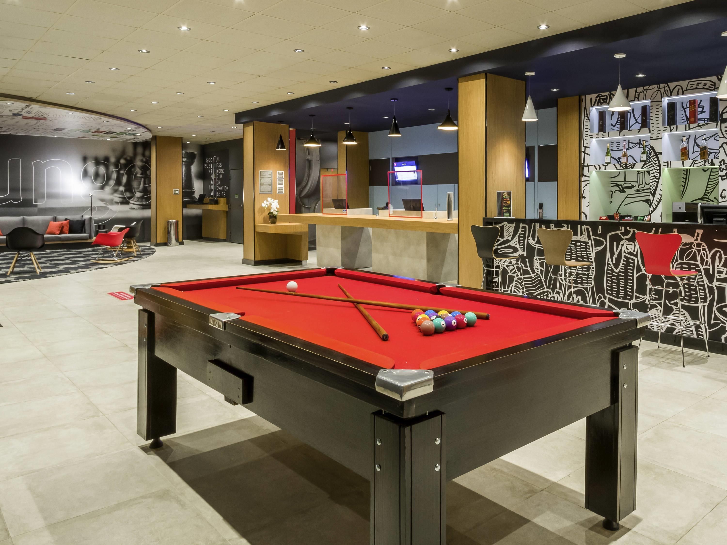 Une table de billard avec des billes, un comptoir d’accueil et un mur orné d’œuvres d’art abstraites.