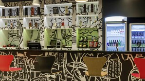 Una zona de bar con estantes llenos de licores, una máquina de café y asientos con sillas y mesas.