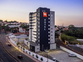 Un moderno edificio de hotel con un llamativo logotipo de 'ibis', varios pisos y un área de estacionamiento.