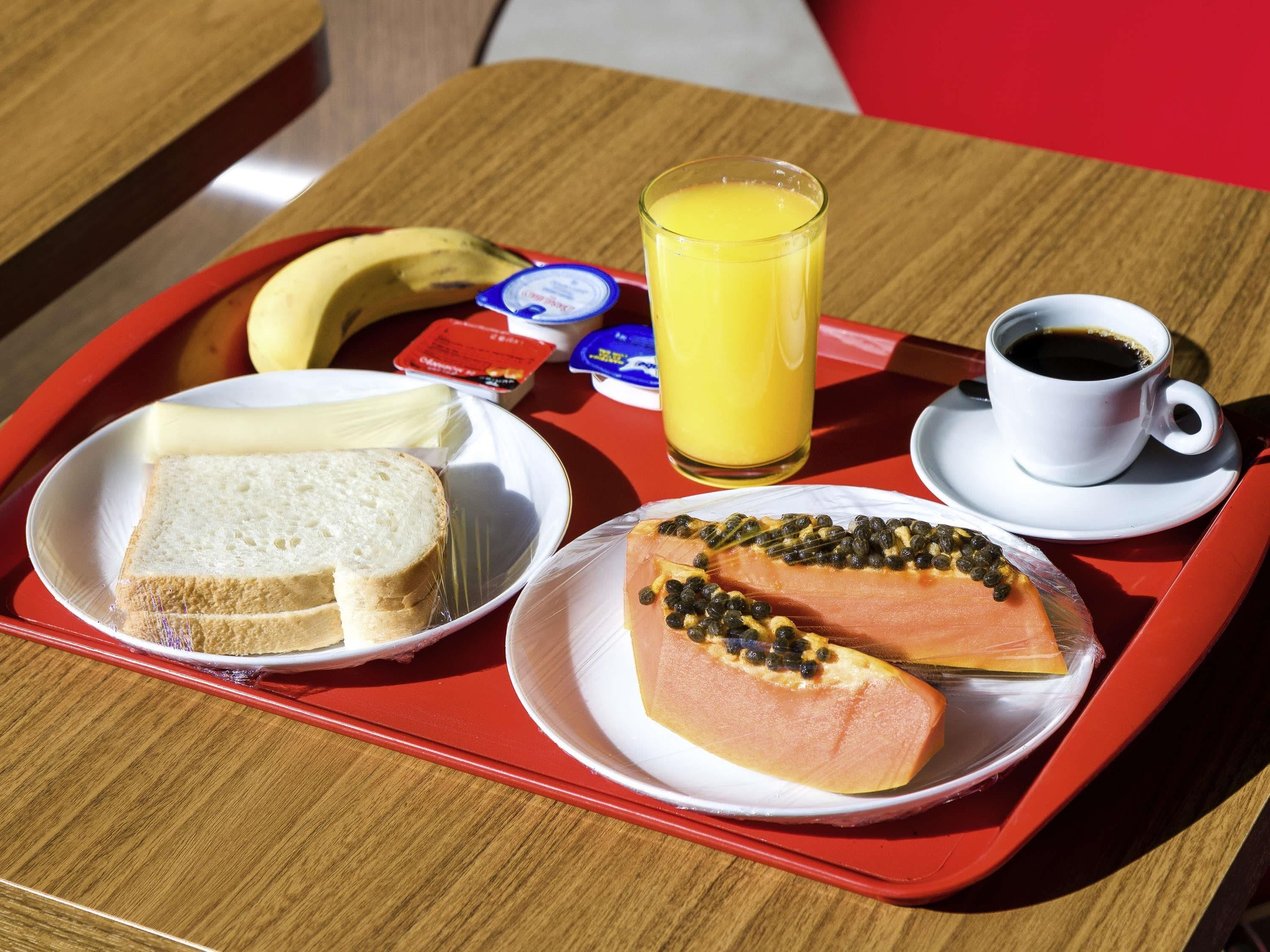 A tray with a sandwich, a glass of orange juice, a cup of coffee, and a banana.