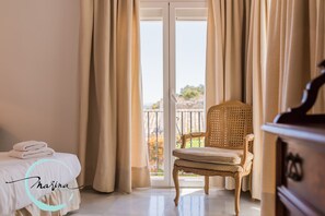 A hotel room with a bed, a chair, a dresser, and a balcony with curtains. - APARTAMENTOS PUERTO MARINA DEL ESTE (Almunecar)