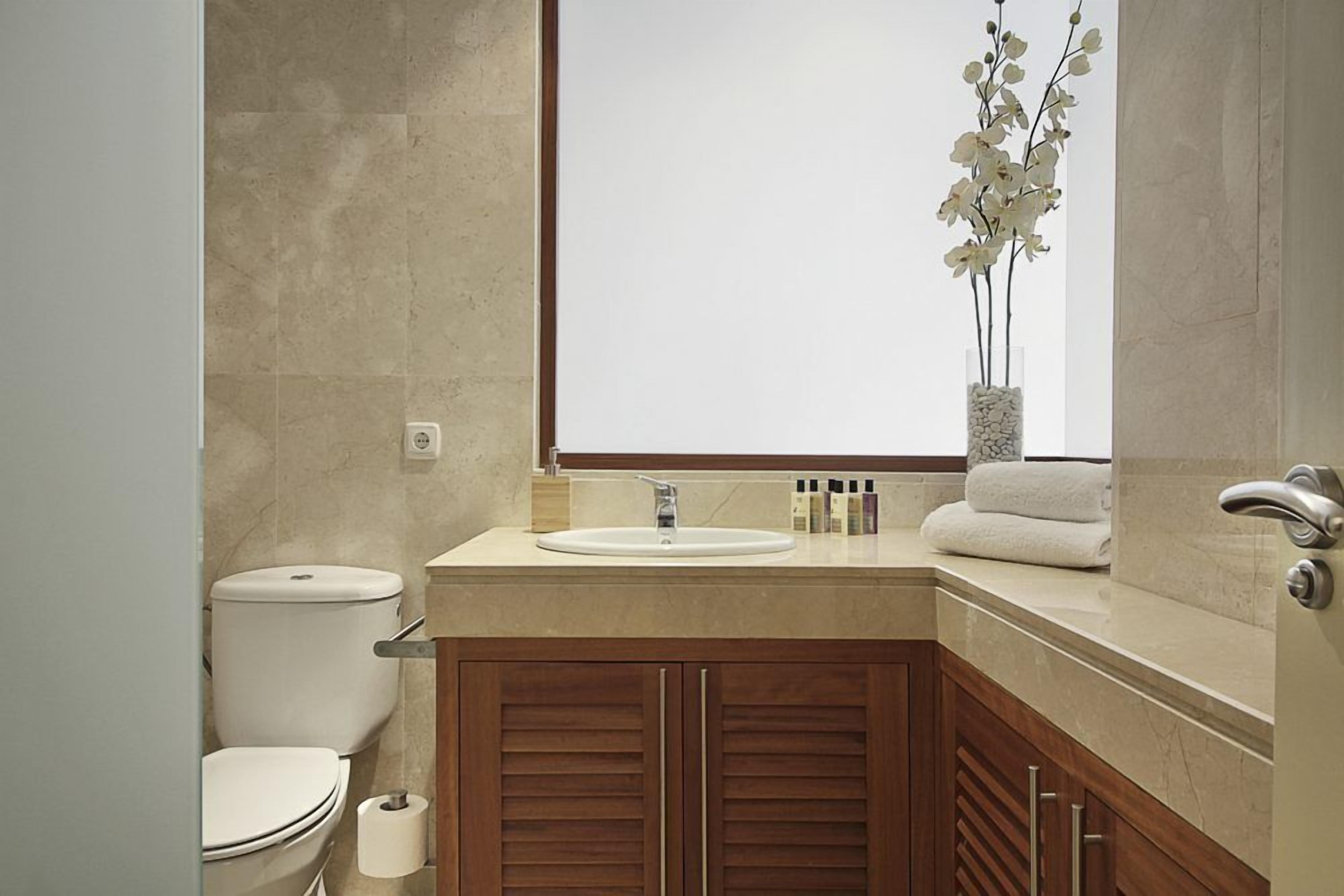 Een badkamer met toilet, wastafel en houten kastjes.