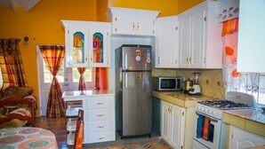 Une cuisine avec des armoires blanches, un réfrigérateur en acier inoxydable, une cuisinière à gaz et un four à micro-ondes.