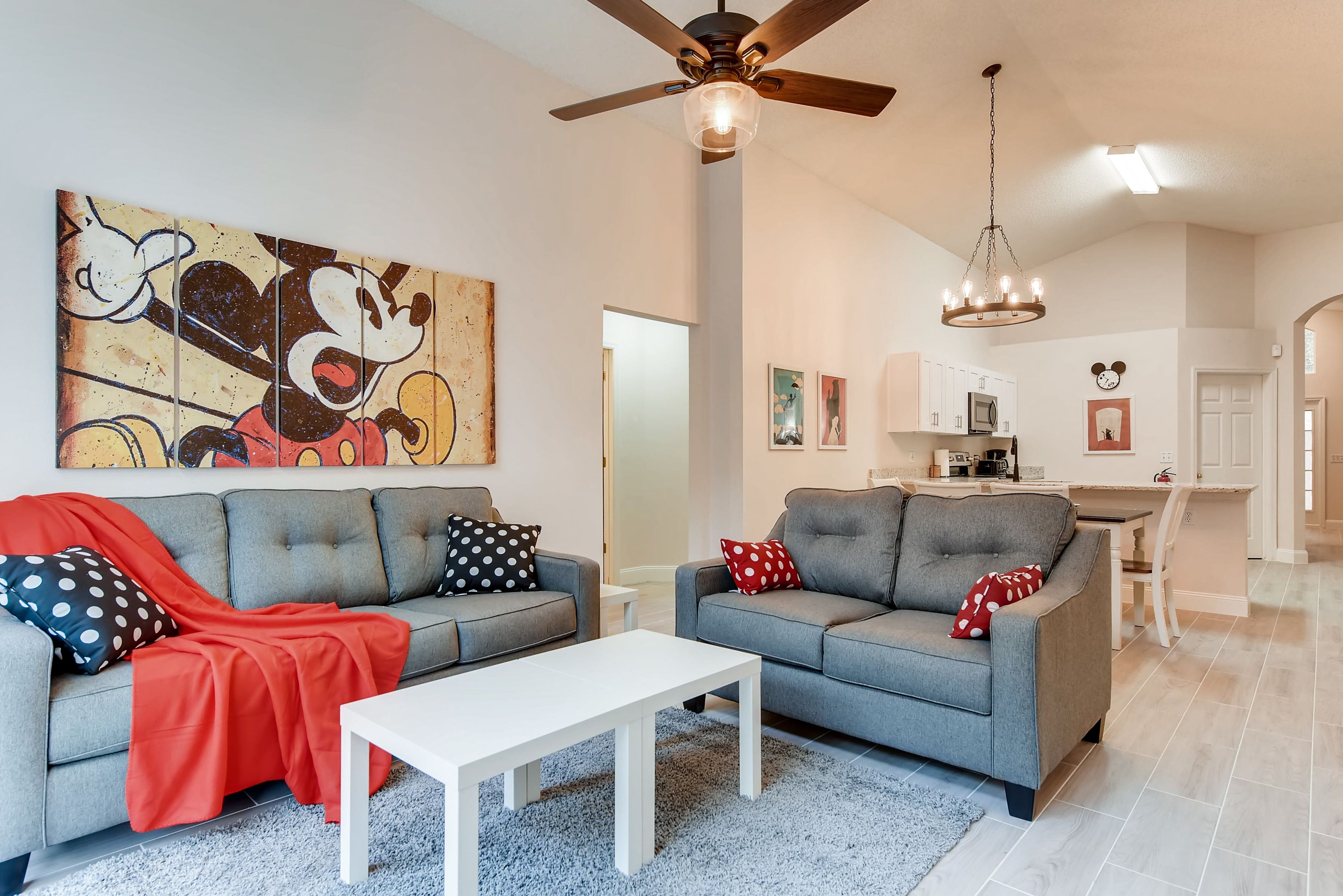 A modern living room with two grey sofas, a white coffee table, and a ceiling fan.