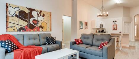 A modern living room with two grey sofas, a white coffee table, and a ceiling fan.