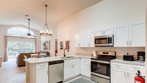Una cocina moderna con armarios blancos, electrodomésticos de acero inoxidable y una isla central.
