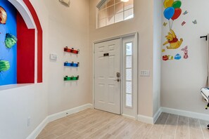 Un pasillo con una puerta blanca, una ventana y una pared con un mural de Winnie the Pooh.