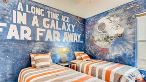 Un dormitorio con dos camas, un mural temático de galaxia y una ventana.