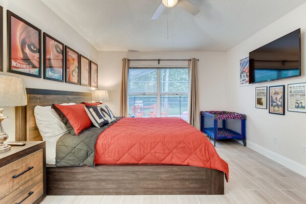 A bedroom with a bed, a nightstand, a lamp, a window with curtains, a bunk bed, and posters on the wall.