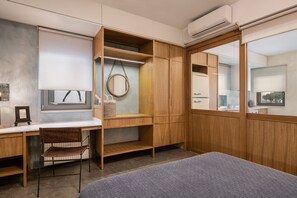 Une chambre moderne avec un bureau en bois, une chaise, un lit et une armoire dotée d’un miroir.