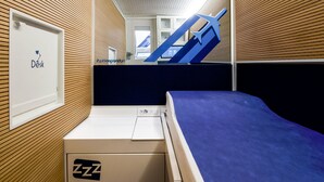 Una habitación pequeña con cama, escritorio y ventana.
