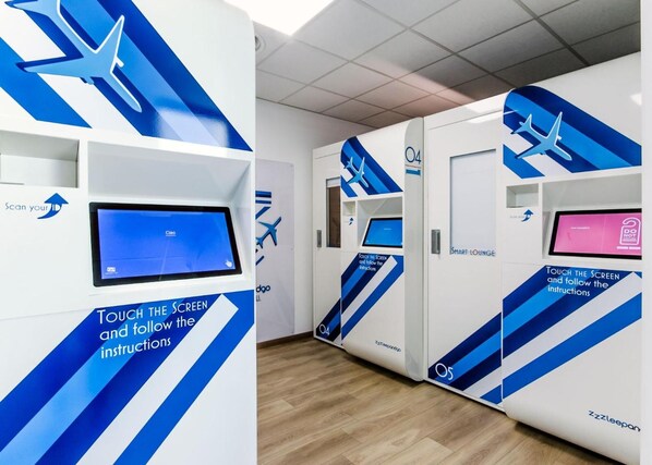 A modern airport lounge with interactive kiosks and digital screens for passenger services. - ZZZLeepandgo TRN Aeroporto Torino (Caselle Torinese)