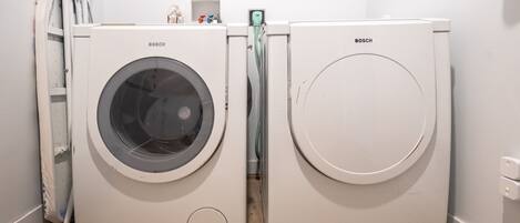 Deux machines à laver Bosch dans une buanderie avec un mur blanc et un plancher en bois.