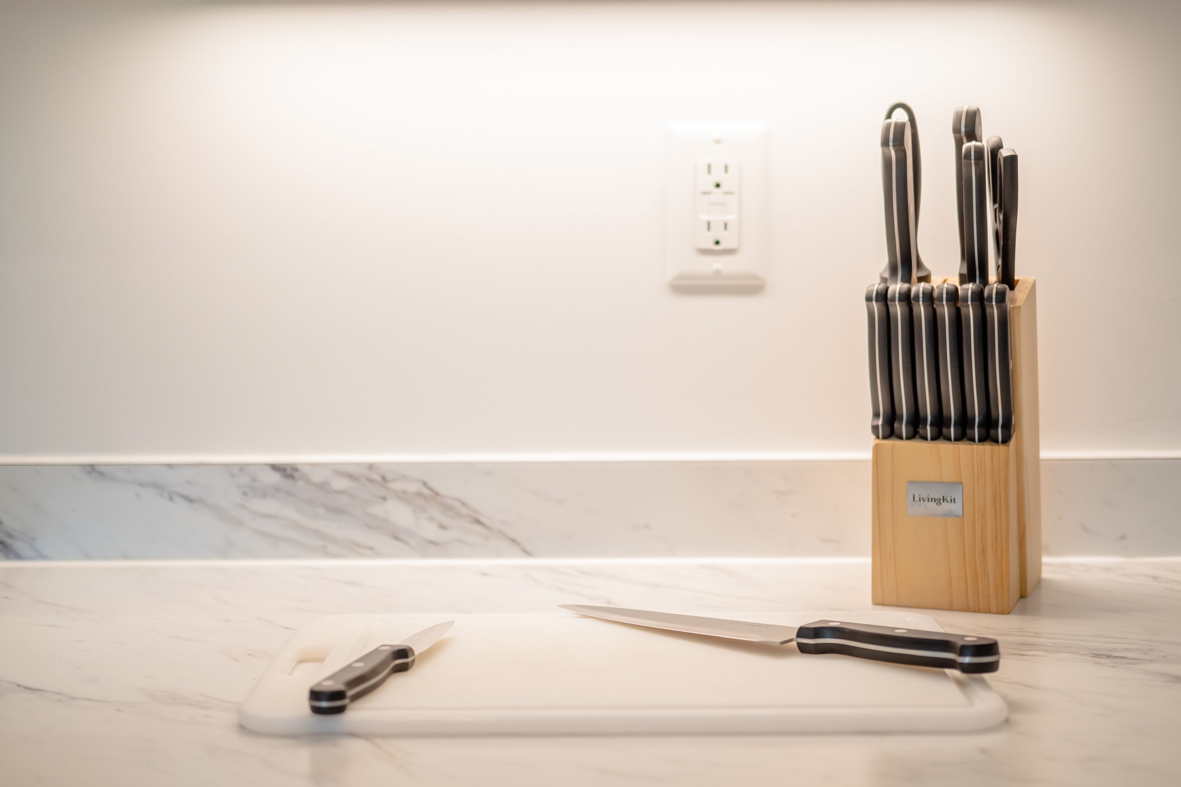 A kitchen counter with a knife block, a cutting board, and a knife.
