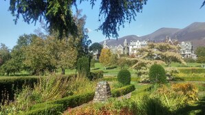 Um edifício grande e histórico com várias torres e um jardim bem cuidado na frente.