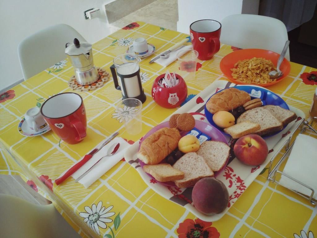 Ein Esstisch gedeckt mit Frühstücksleckereien, darunter Brot, Obst und eine Kaffeekanne.