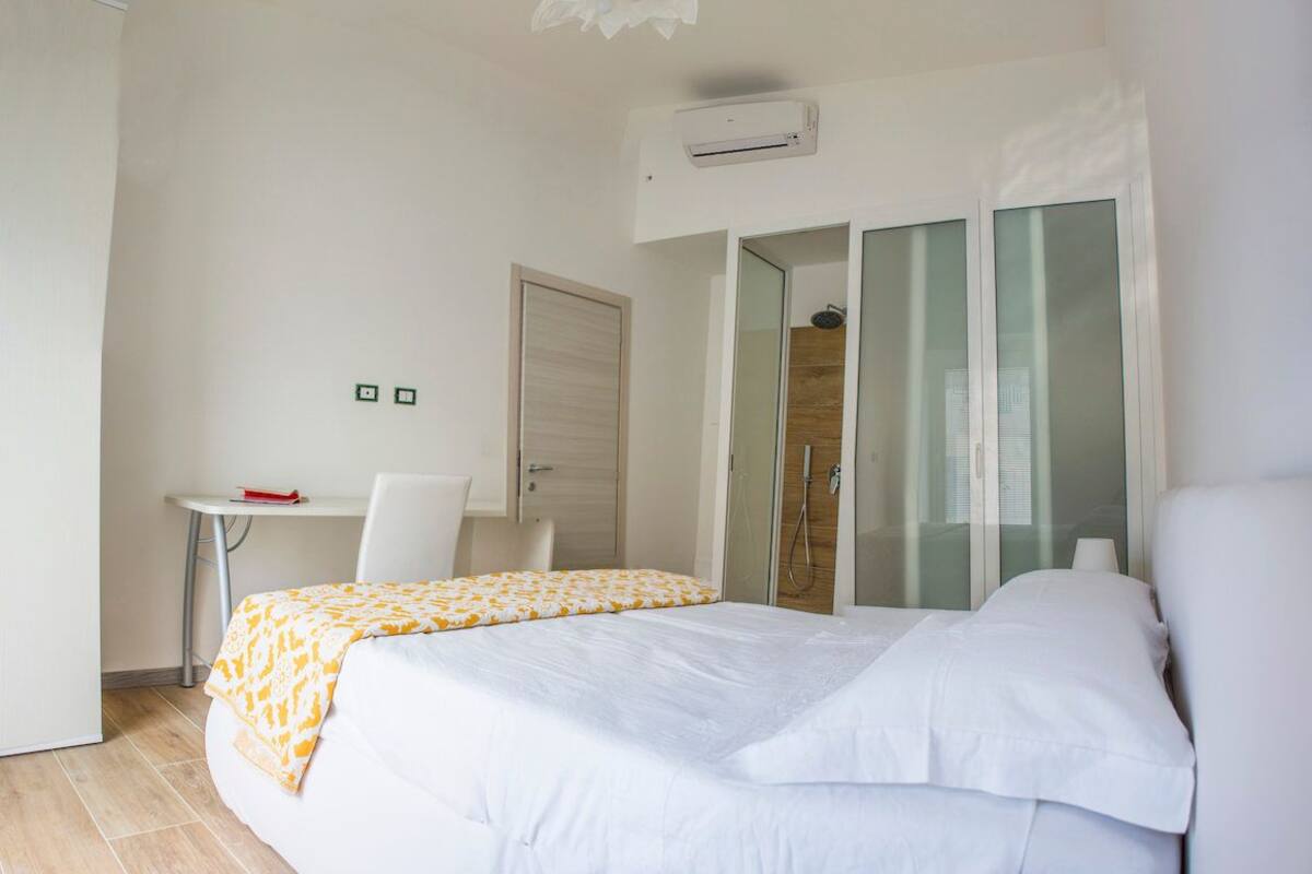 A bedroom with a bed, a desk, and a chair.