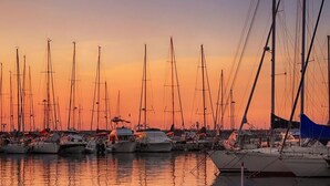 Un puerto deportivo lleno de veleros al atardecer.