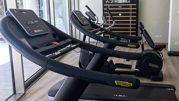 A gym with treadmills, a weight bench, and a wall-mounted exercise machine.